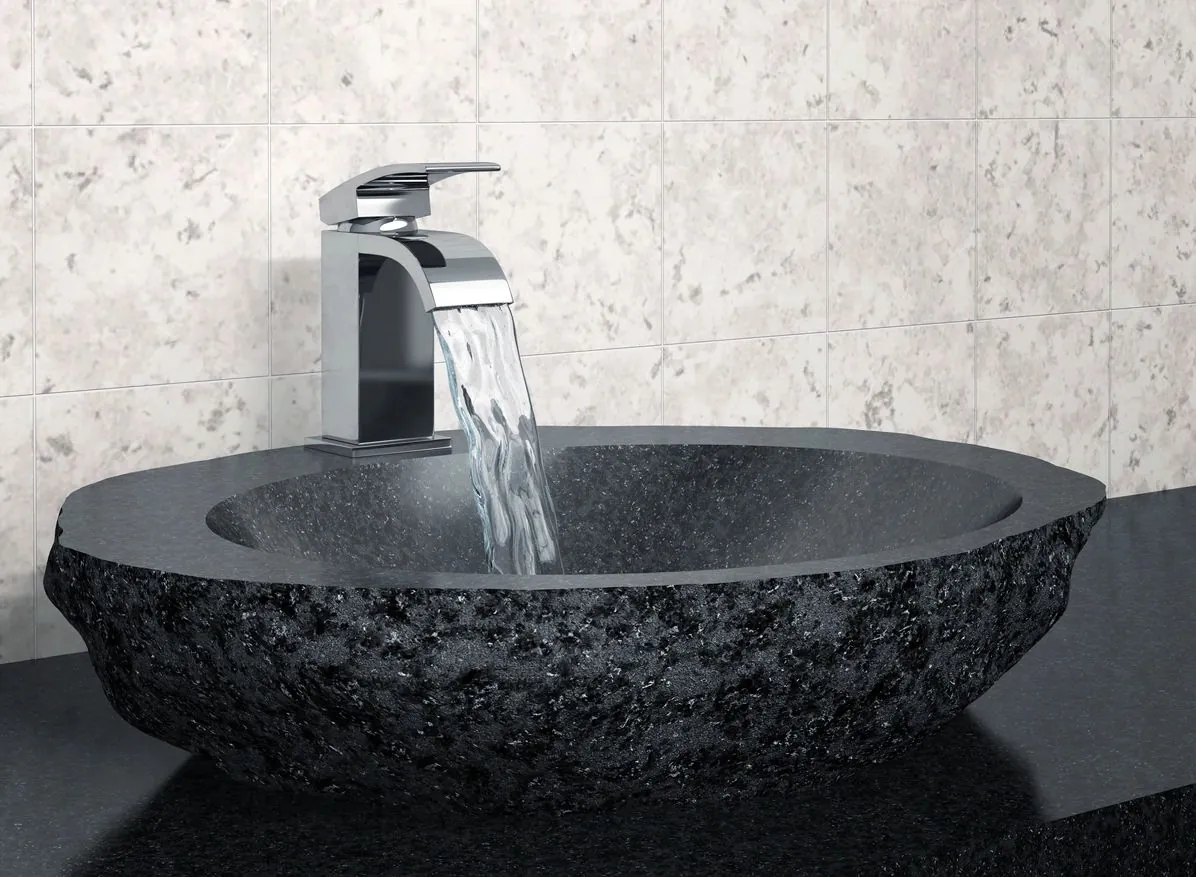 Waterfall faucet flowing into a black stone basin