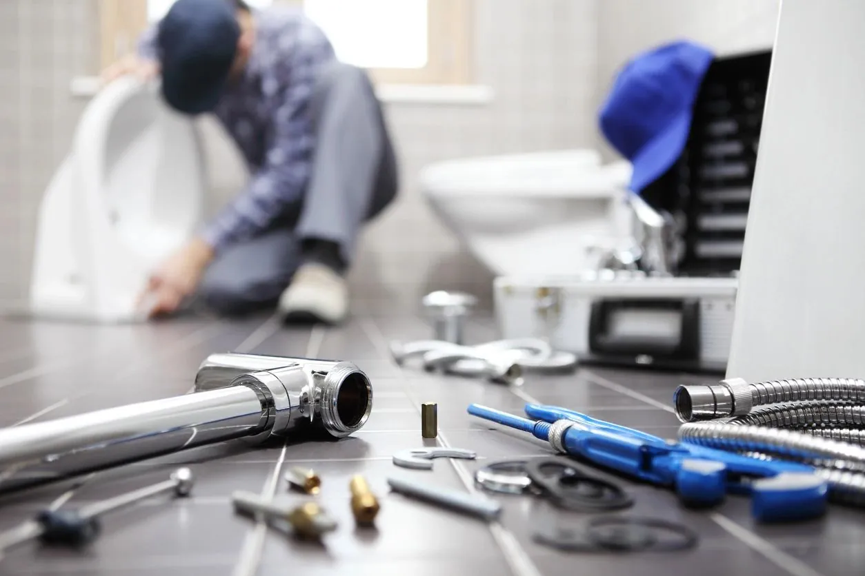 Plumbing technician working on a bathroom repair with tools